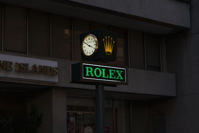 Rolex sign with clock and crown logo outside a building.